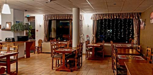 um restaurante com mesas e cadeiras de madeira e uma janela em Hotel Les Bruyères em Alpe-dʼHuez