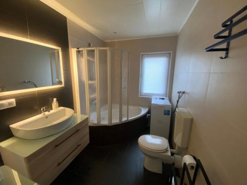 a bathroom with a sink and a toilet and a tub at EIFELCOTTAGE Zaunkönig in Ulmen