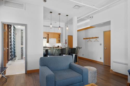 a living room with a blue chair and a kitchen at Savoy Hotel in Nelson