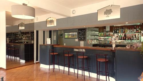 a bar in a restaurant with stools at Hôtel Sous l'Olivier in Buis-les-Baronnies