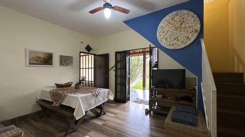 Una sala de estar con una mesa y un televisor. en Casa c piscina a 700m da Praia de Caraguatatuba SP, en Caraguatatuba