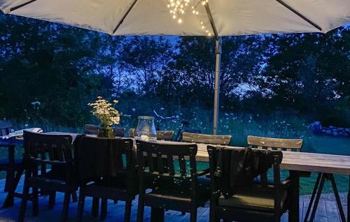 a wooden table with chairs and an umbrella at Gorgeous Home In Köpingsvik With Wifi in Köpingsvik