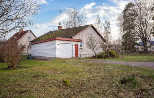 a white house with a red door in a yard at 2 Bedroom Lovely Home In Mörlunda in Mörlunda