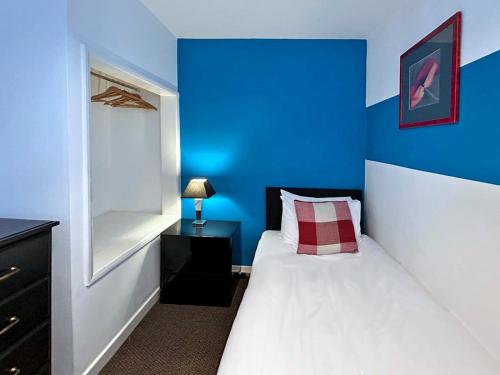 a blue bedroom with a bed and a blue wall at Cosy & convenient Consett flat in Consett