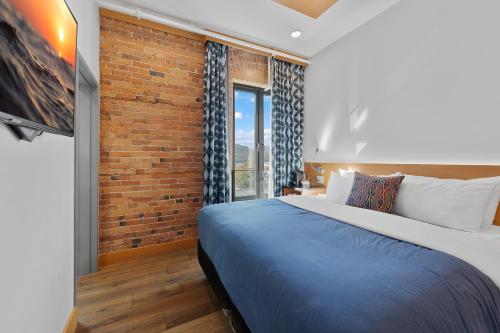 a bedroom with a bed and a brick wall at Savoy Hotel in Nelson