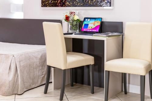 a desk with a laptop and two chairs at Hotel Demo' in Milan