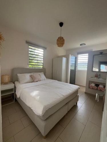 a bedroom with a large white bed and windows at Cocobana 20 - 2 bedroom apartment in Willemstad
