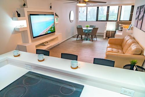 a living room with a couch and a tv at Beachfront Bliss at Isla Verde in San Juan
