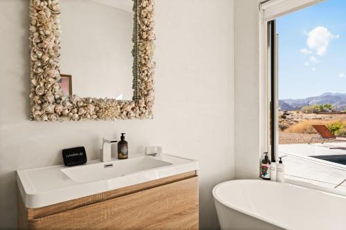 a bathroom with a white sink and a mirror at Beyond - Walk to Red Dog & Pappy's in Pioneertown