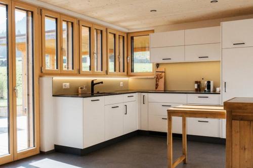 a kitchen with white cabinets and a table at Hidden Retreats The MountainHut in Wengi bei Frutigen