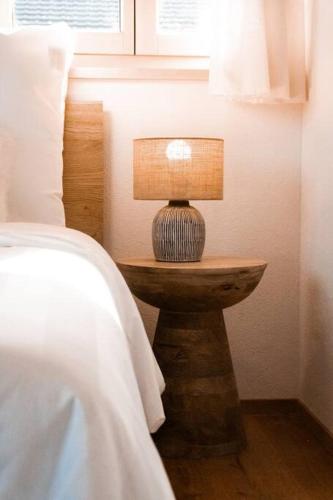 a lamp on a wooden table next to a bed at Hidden Retreats The MountainHut in Wengi bei Frutigen