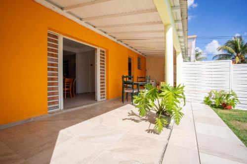 a patio with an orange wall and a table at Vaniya in Fonds dʼ Or