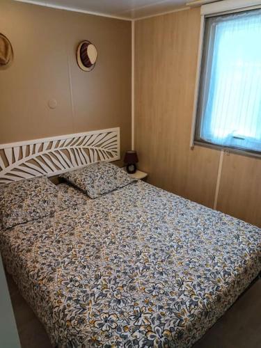 une chambre avec un lit avec une couette et une fenêtre dans l'établissement Mobil-Home 4 places dans les Landes, à Saint-Julien-en-Born
