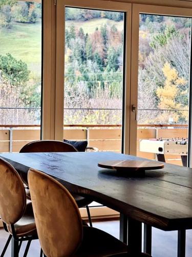 a wooden table with chairs in front of a window at Hidden Retreats The Niesen in Reichenbach