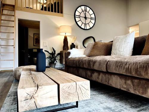 a living room with a couch and a clock on the wall at Hidden Retreats The Niesen in Reichenbach