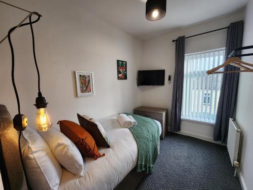 a bedroom with a bed with pillows and a window at Contractor Base - 2 Baths - Smart TVs in Rooms in Swansea