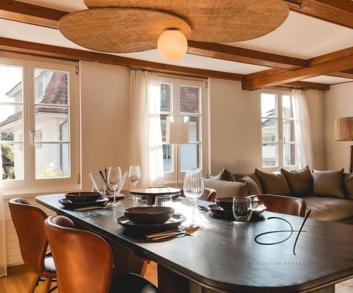 a dining room with a table with chairs and a couch at Hidden Retreats The Seehof 1 in Oberhofen am Thunersee