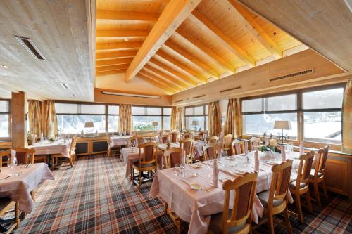 een eetkamer met tafels, stoelen en ramen bij Serviced Apartments – Kirchbühl@home in Grindelwald