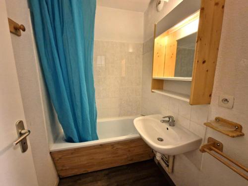La salle de bains est pourvue d'un rideau de douche bleu et d'un lavabo. dans l'établissement Résidence Grand Argentier - 2 pièces +cabine 4/6 personnes coeur station 32m² MAE-2922, à Modane