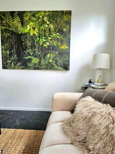 a living room with a couch and a painting on the wall at Karamu- Spacious, quiet, and close to amenities in Masterton