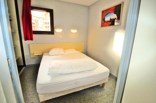 une petite chambre avec un lit avec des draps blancs et des oreillers dans l'établissement Résidence Les Balcons De La Vanoise - LES BALCONS DE LA VANOISE - BV406 MAE-3186, à Villarodin-Bourget