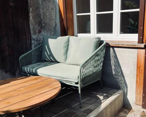 a green wicker chair sitting on a porch with a table at Hidden Retreats The Seehof 2 in Oberhofen am Thunersee