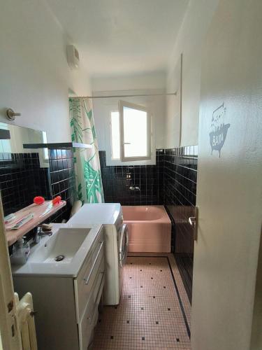 La salle de bains est pourvue d'une baignoire rose et d'un lavabo. dans l'établissement Chambre Cosy proche de la gare, à Toulouse