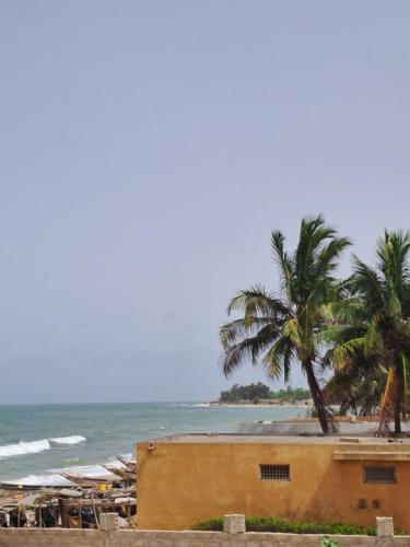 a beach with a building and palm trees and the ocean at Senebreizh in Somone
