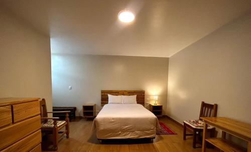 a bedroom with a bed and two chairs and a table at Alpamayo Casa Hotel - Restaurante in Yungay