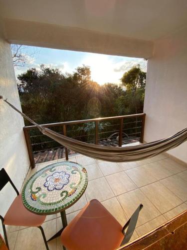 a balcony with a hammock and a table and chair at Villa Macacos in Nova Lima
