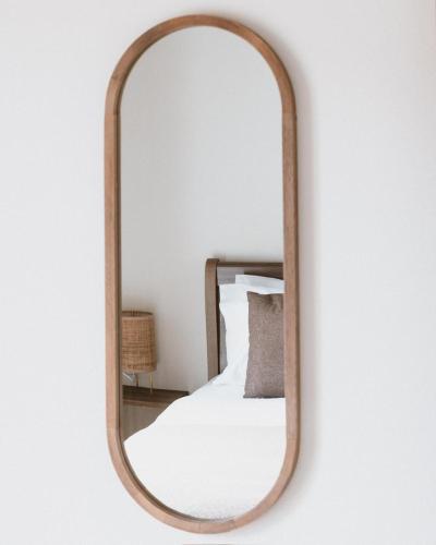 a mirror with a wooden frame hanging on a wall at The Yard Residence in Gavalochori