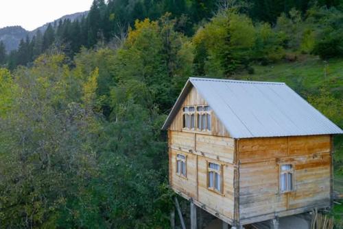 a wooden house with a metal roof in a forest at Hotel Voisa/სასტუმრო ვოისა in Batumi
