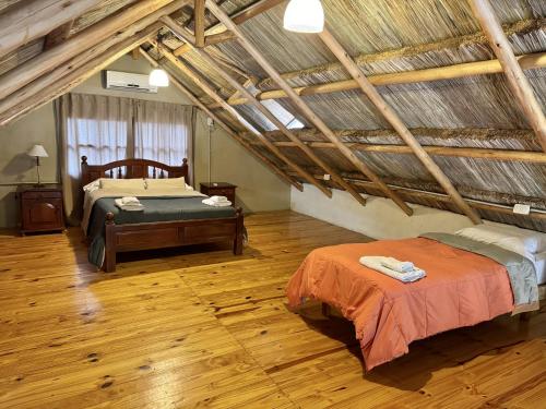 ein Schlafzimmer im Dachgeschoss mit zwei Betten und Holzböden in der Unterkunft Alojamiento La Victoria in San Rafael
