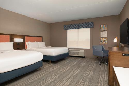 a hotel room with two beds and a desk at Hampton Inn by Hilton Port Hope Cobourg in Port Hope