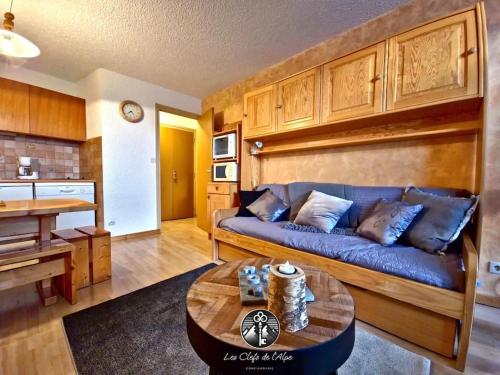 un salon avec un canapé bleu et une table dans l'établissement Nouveau ! Logement lumineux - Centre station - Cozy, à Huez