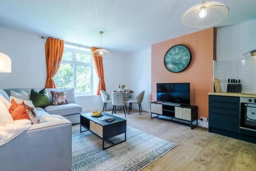 a living room with a couch and a clock on the wall at ANCHORAGE APARTMENT 5 - Two bed apartment close to the centre and the beach, located in Llandudno, North Wales in Llandudno
