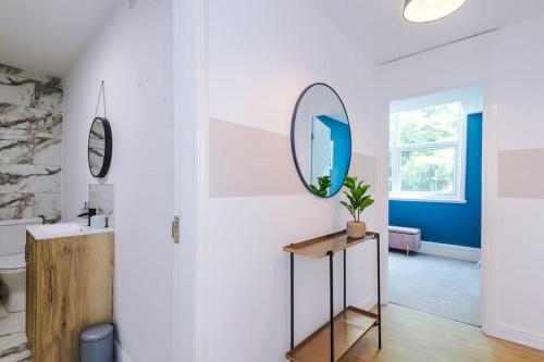 a bathroom with a mirror and a table with a plant at ANCHORAGE APARTMENT 5 - Two bed apartment close to the centre and the beach, located in Llandudno, North Wales in Llandudno