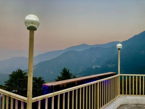 a balcony with a street light and mountains in the background at Hotel Redchilli in Dalhousie