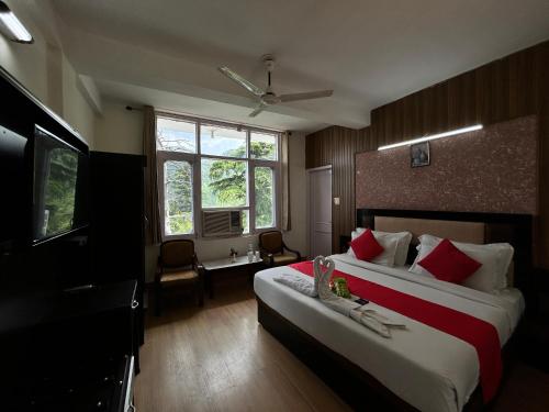 a hotel room with two beds and a television at Hotel Redchilli in Dalhousie