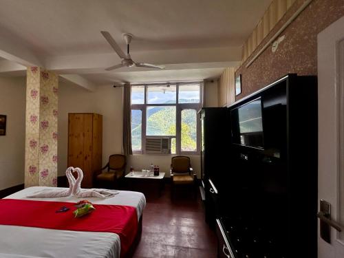 a hotel room with a bed and a flat screen tv at Hotel Redchilli in Dalhousie