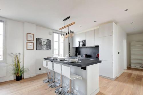 une cuisine avec des armoires blanches et un comptoir noir dans l'établissement Suite Modern Art - Superbe appartement, à Suresnes
