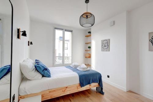 - une chambre blanche avec un lit et des oreillers bleus dans l'établissement Suite Modern Art - Superbe appartement, à Suresnes