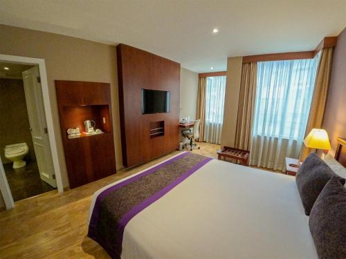 a hotel room with a large bed and a television at Mercure Alameda Quito in Quito