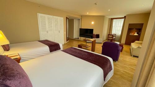 a hotel room with two beds and a television at Mercure Alameda Quito in Quito