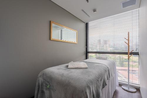 a bedroom with a bed and a large window at Hotel Estelar Square in Medellín