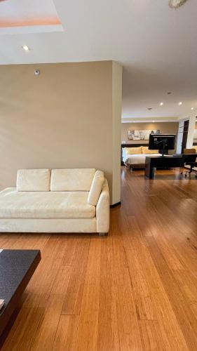 a living room with a white couch and a piano at Mercure Alameda Quito in Quito