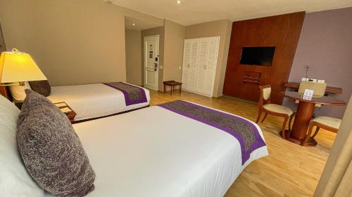a hotel room with two beds and a desk at Mercure Alameda Quito in Quito