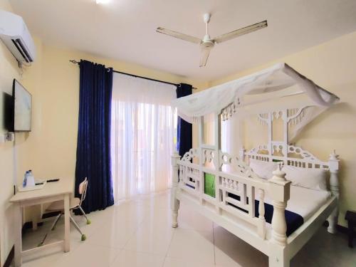 a bedroom with a white bed and a desk at Elna's Nyali - Work & Unwind - Pool, Sea Views, AC & Fast Wi-Fi in Mombasa