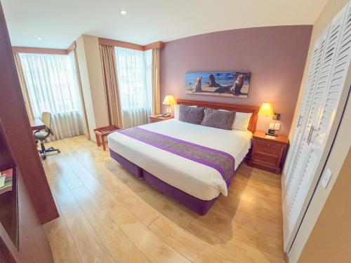 a bedroom with a large bed and two windows at Mercure Alameda Quito in Quito