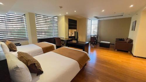 a hotel room with two beds and a desk at Mercure Alameda Quito in Quito